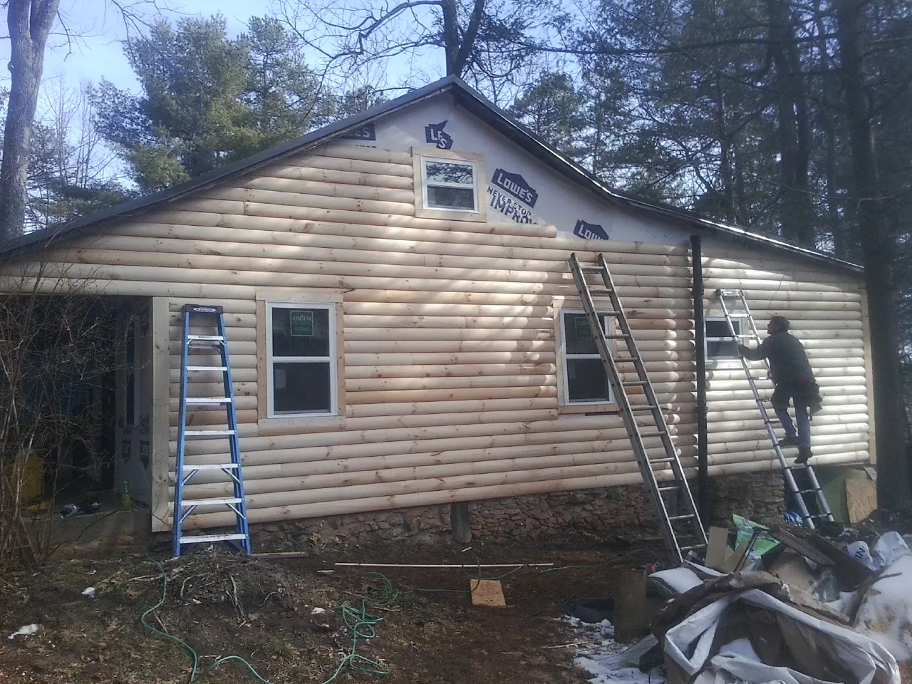 Ladders set against fresh log siding during an exterior remodel in Deer Island
