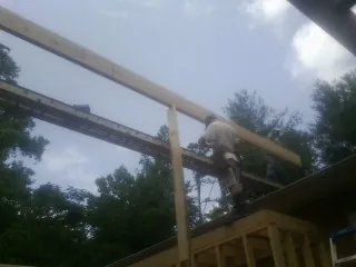 Carpenter setting a ridge beam over a new addition frame — Ice Dam Removal by Roofing Brothers in Deer Island