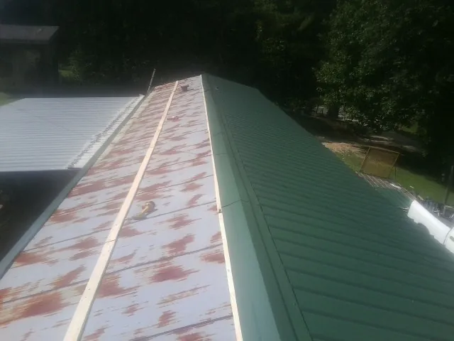 Old rusted panels beside newly installed green metal roofing — Wind Damage Roof Repair by Roofing Brothers in Deer Island