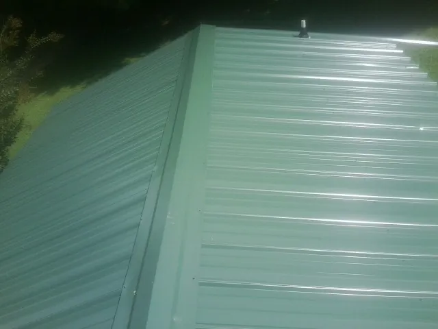 New green metal panels meeting at the ridge of a roof — Flat Roof Repair work by our crew in Deer Island