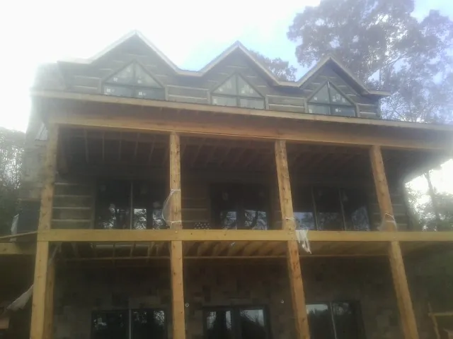 Dormers and porch framing on a large log home under construction — Roof Coating work by our crew in Deer Island