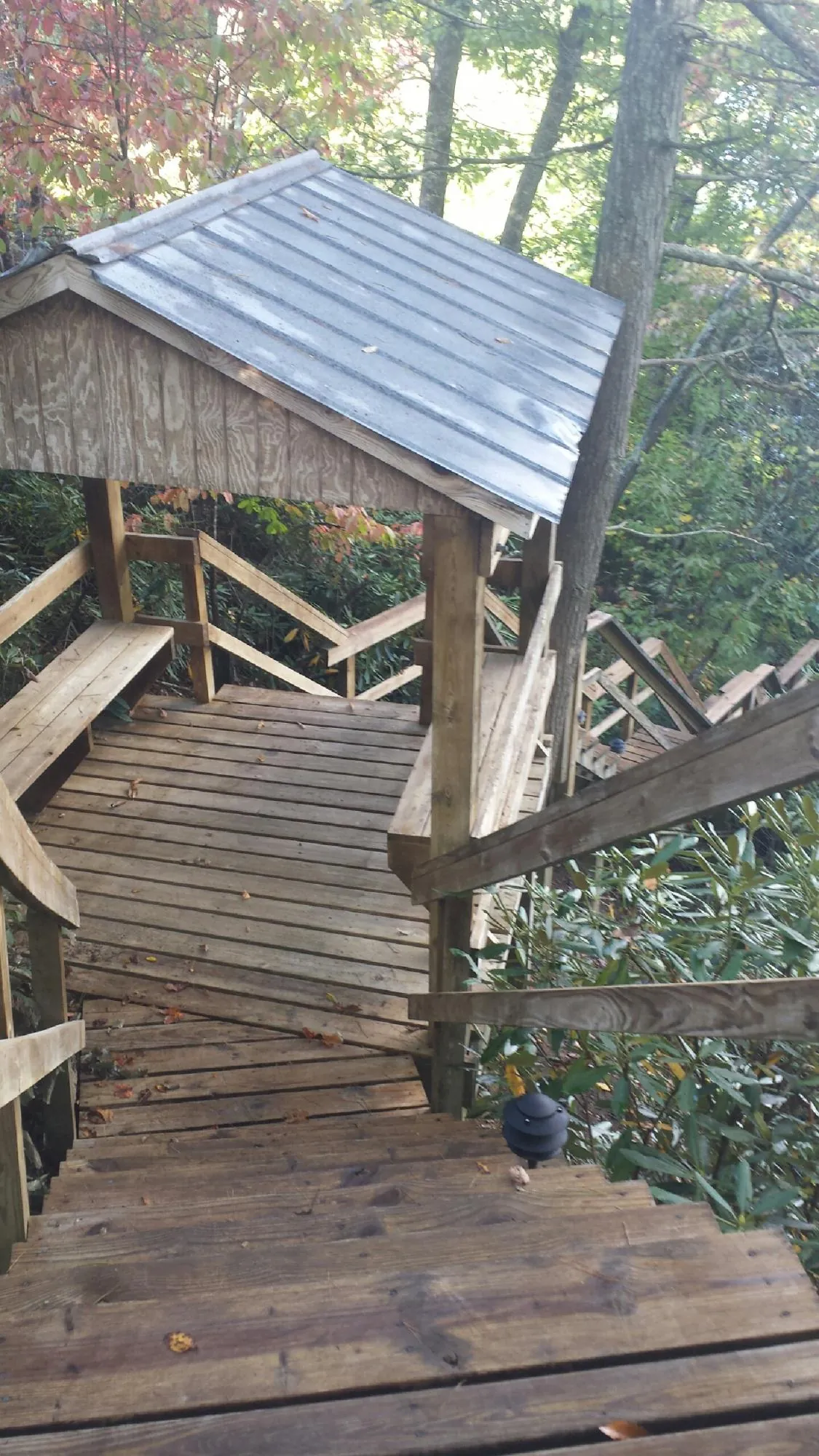 Metal roofed shelter over wooden steps on a wooded walkway — Skylight Repair & Installation work by our crew in Deer Island