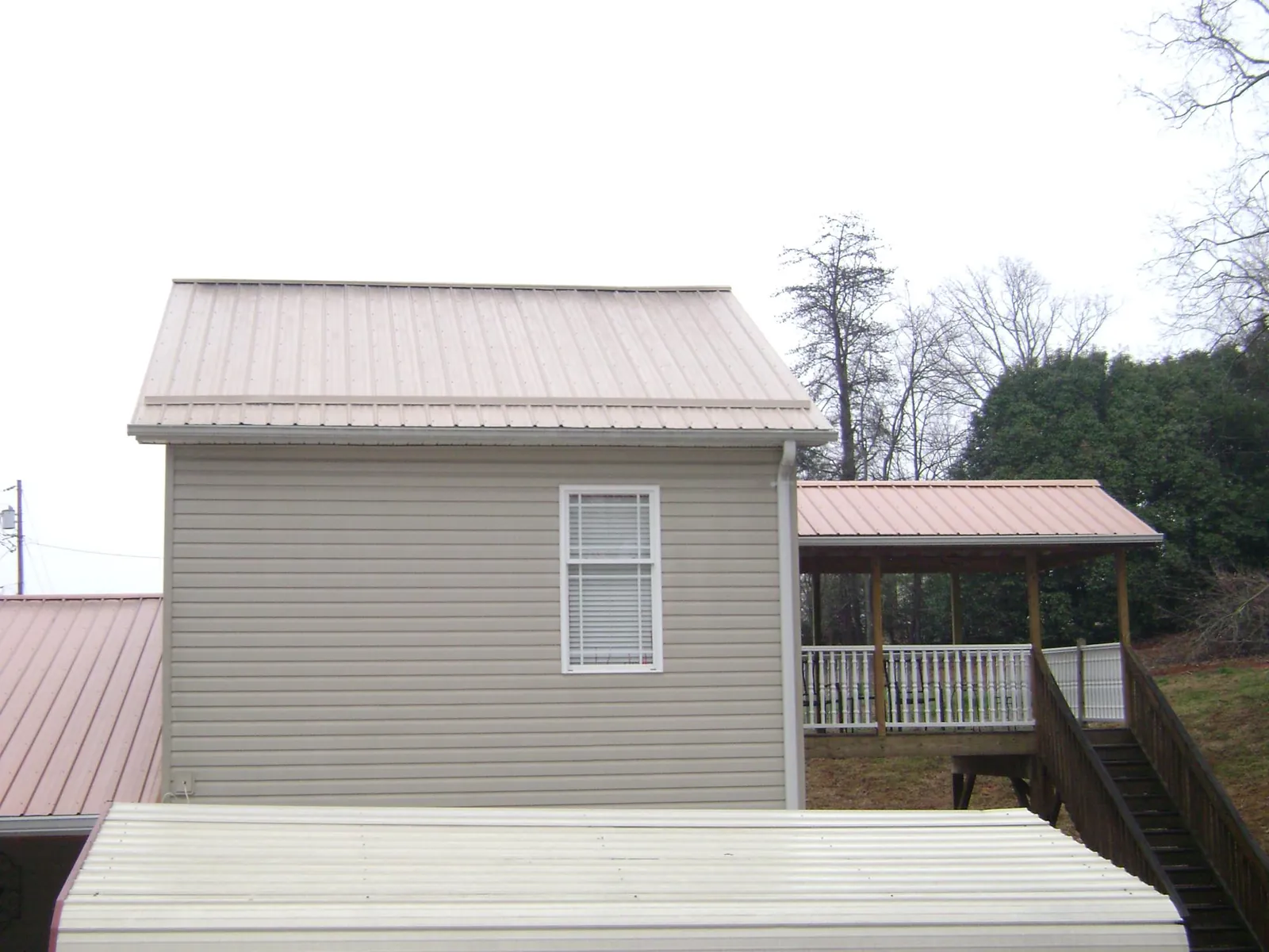 Tan metal roofs on a two story addition and attached porch, from a Roof Replacement job in Deer Island