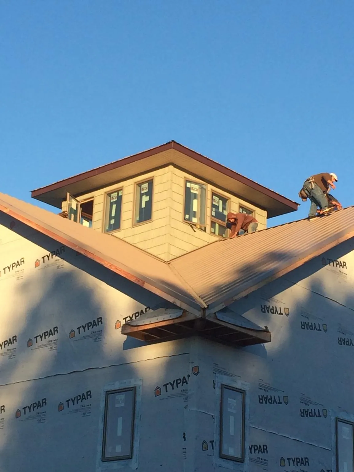 Roofers working around a rooftop cupola on a new metal roof at sunset — Roof Waterproofing in Deer Island by Roofing Brothers